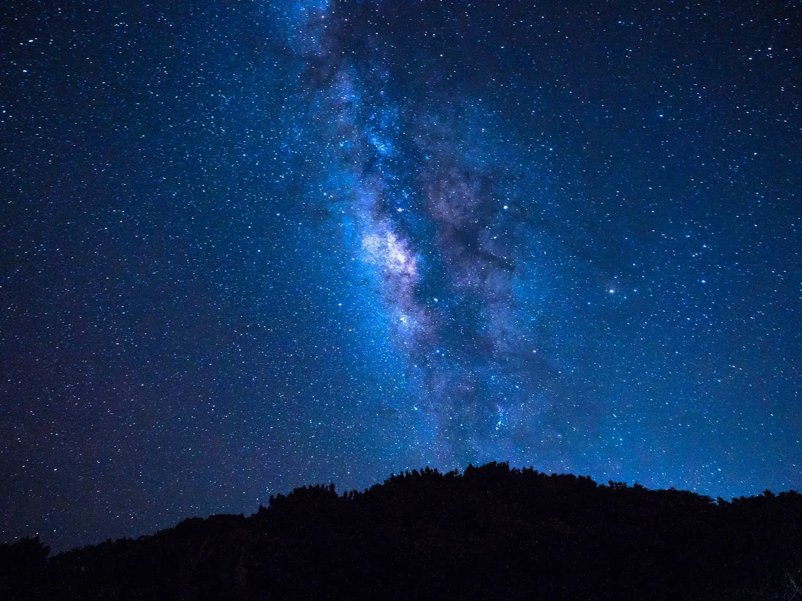 The Milky Way above the dark silhouette of an island in Yaeyama