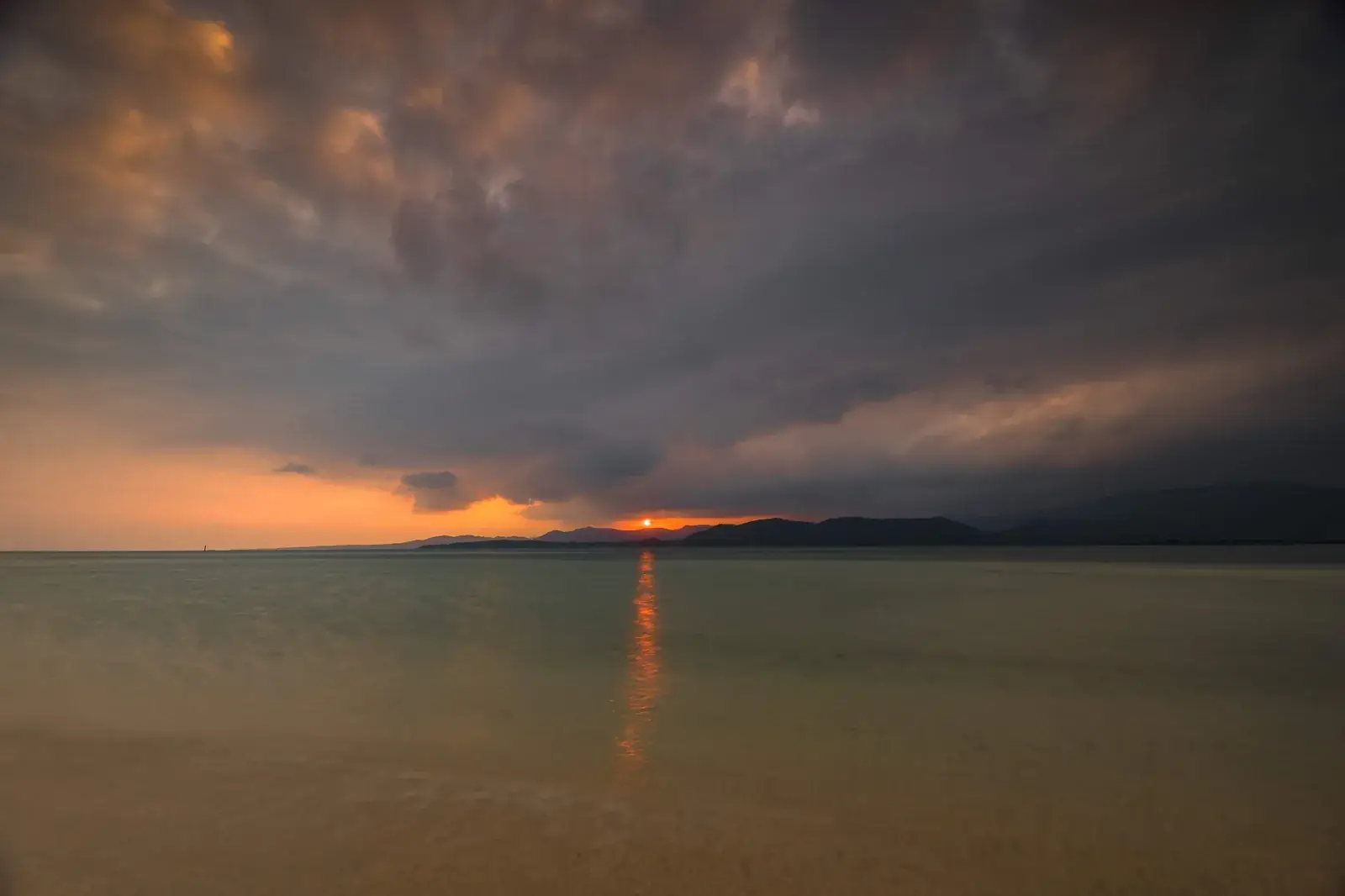 A dark typhoon sky and a narrow band of sunset light seen from Kohama