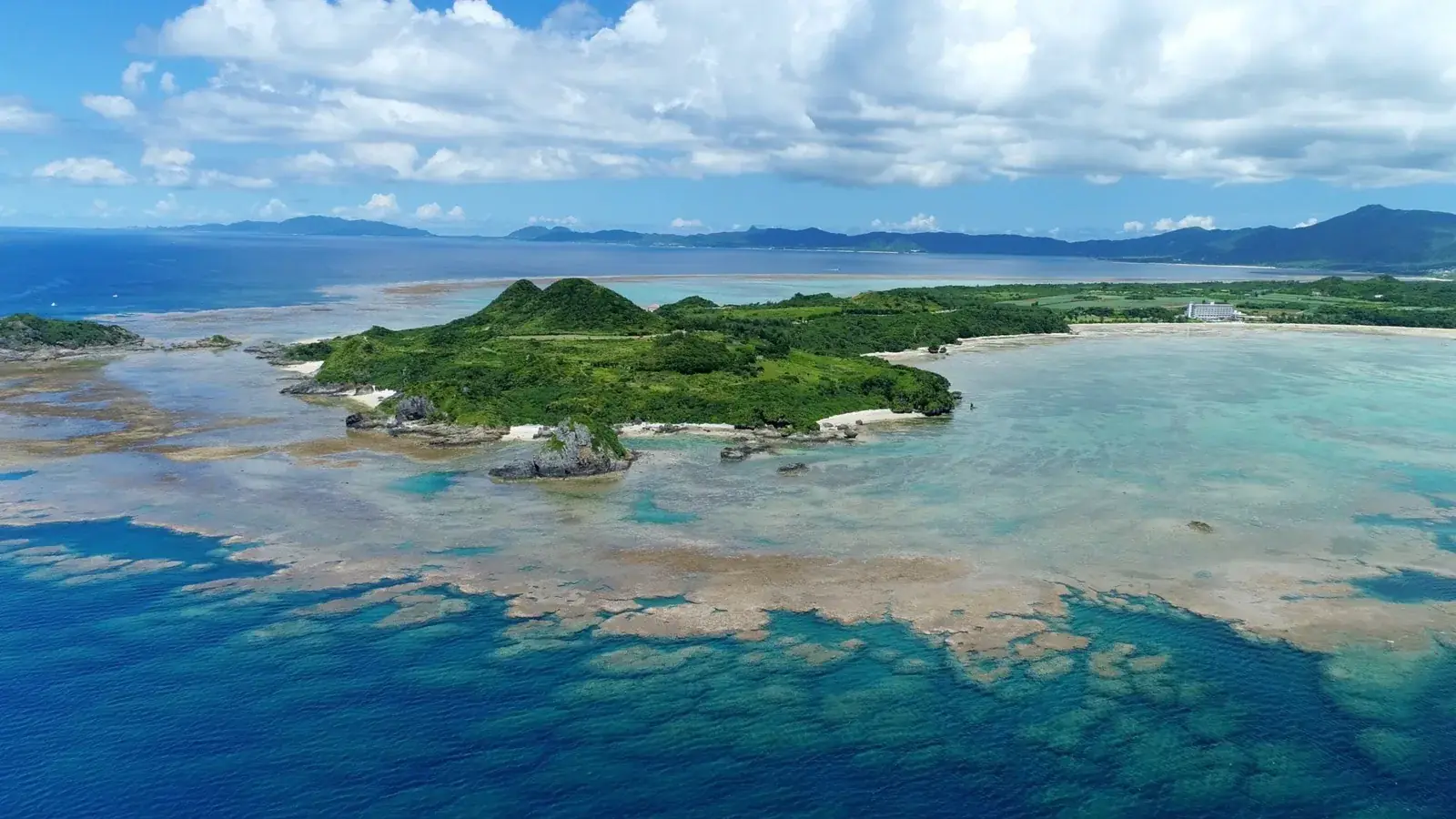 A wide view over reef, blue sea and green coast from Kabira, Ishigaki