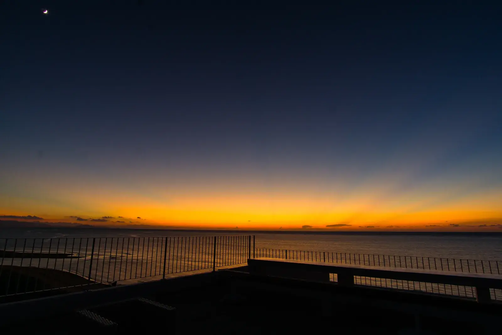 A crescent moon above the last orange light over the sea