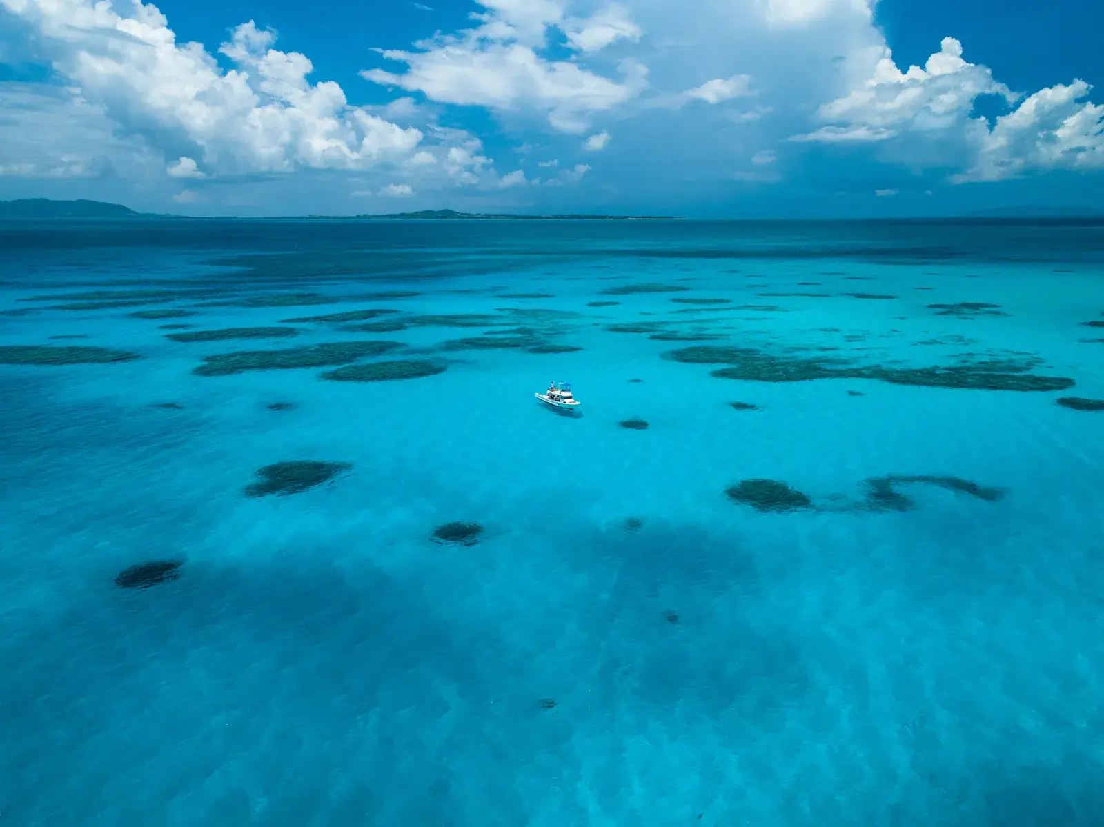 A boat crossing turquoise water between the Yaeyama Islands