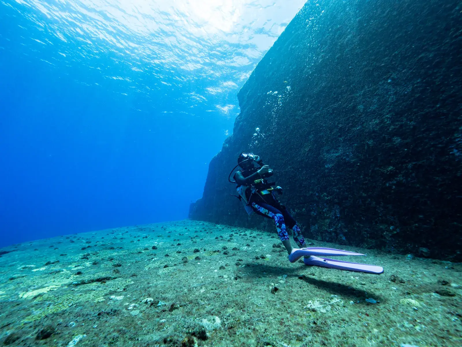 A scuba diver beside an underwater rock wall near Yonaguni Island