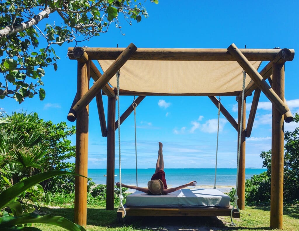 Model jumps on a daybed at the beach at Haimurubushi resort Kohama island
