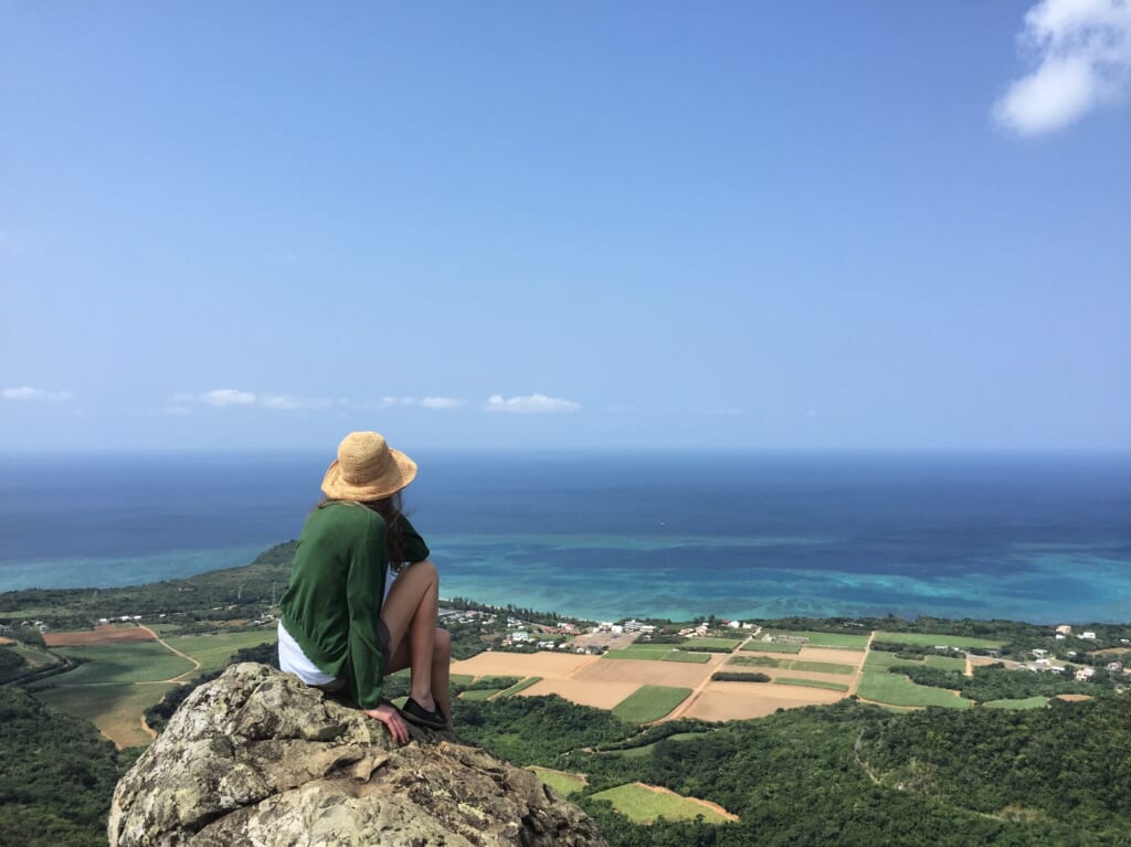 Hiker on top of Mount Nosoko Mape with panoramic view over Ishigaki Island.