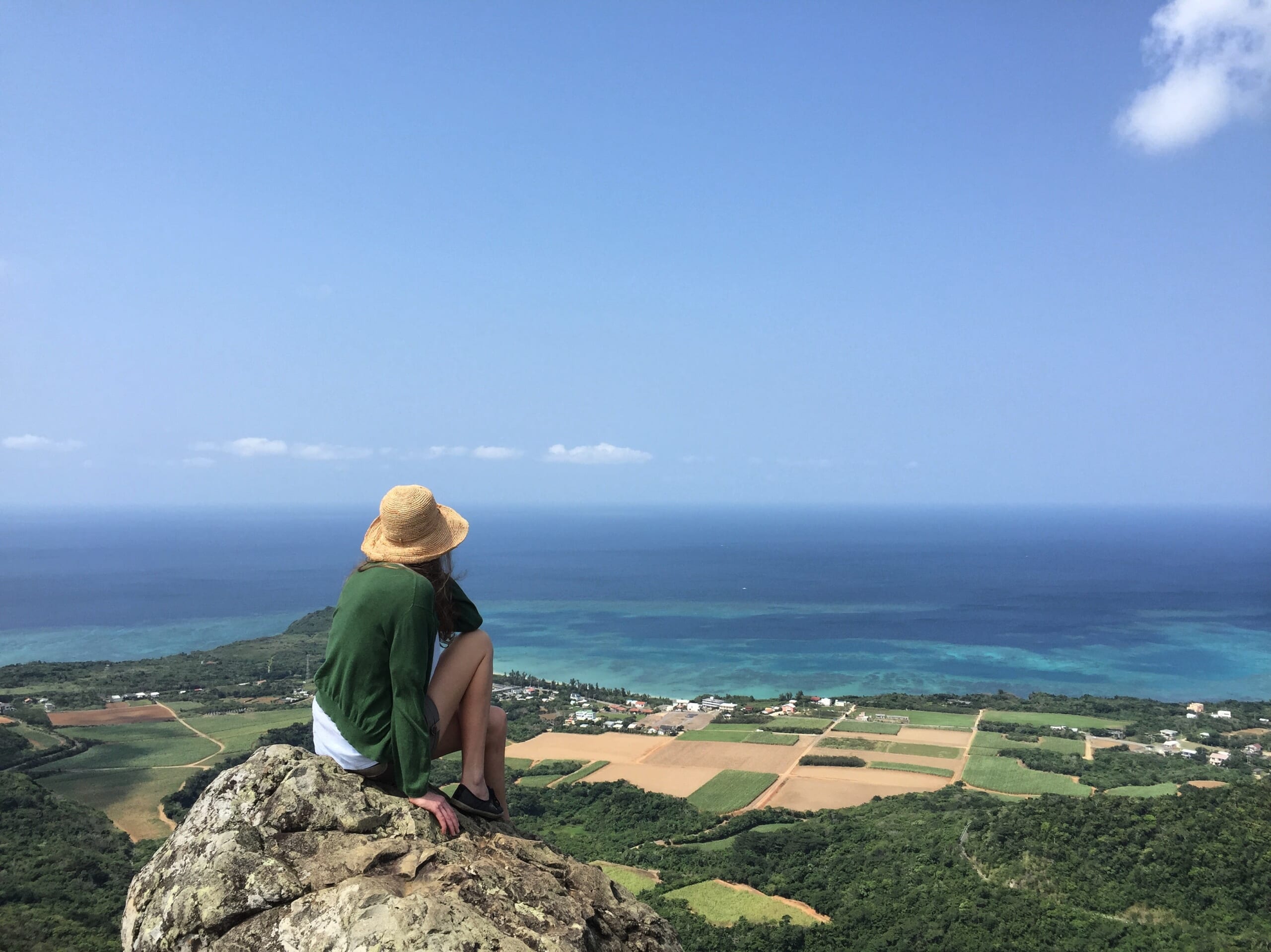 Hiker on top of Mount Nosoko Mape with panoramic view over Ishigaki Island.