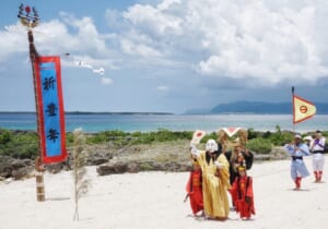 Miruku, the fertility god from Niraikanai with local children around with views on the ocean around Kuroshima island