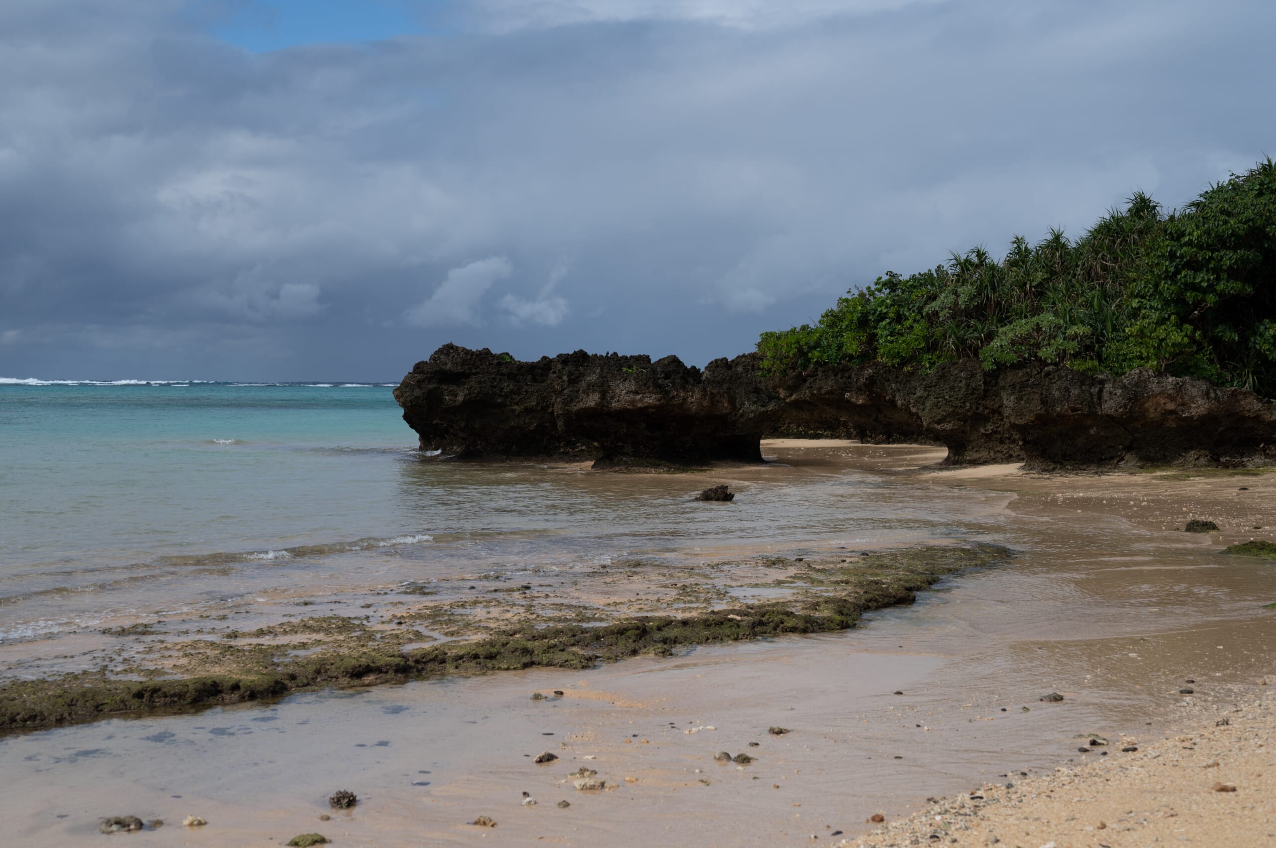 Rain clouds over a rocky shoreline and turquoise water on Ishigaki Island